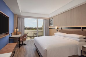 A hotel room with a bed, desk, chair, and a view of the city. - Four Points by Sheraton Nashik (Nashik)