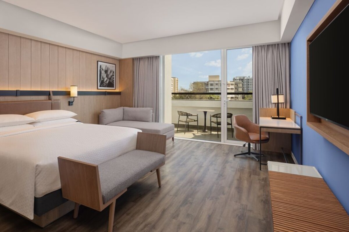 Une chambre d’hôtel avec un grand lit, un bureau, une chaise et un balcon avec vue.