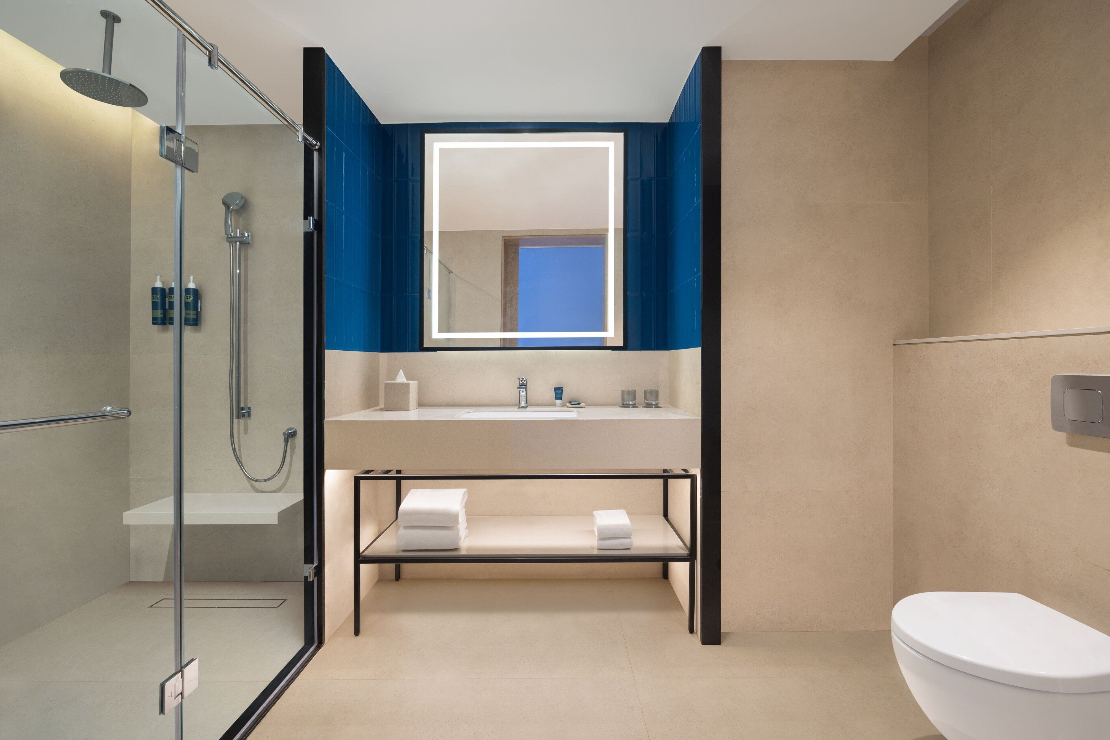A modern bathroom with a glass-enclosed shower, a white sink with a mirror above it, and a toilet to the right.