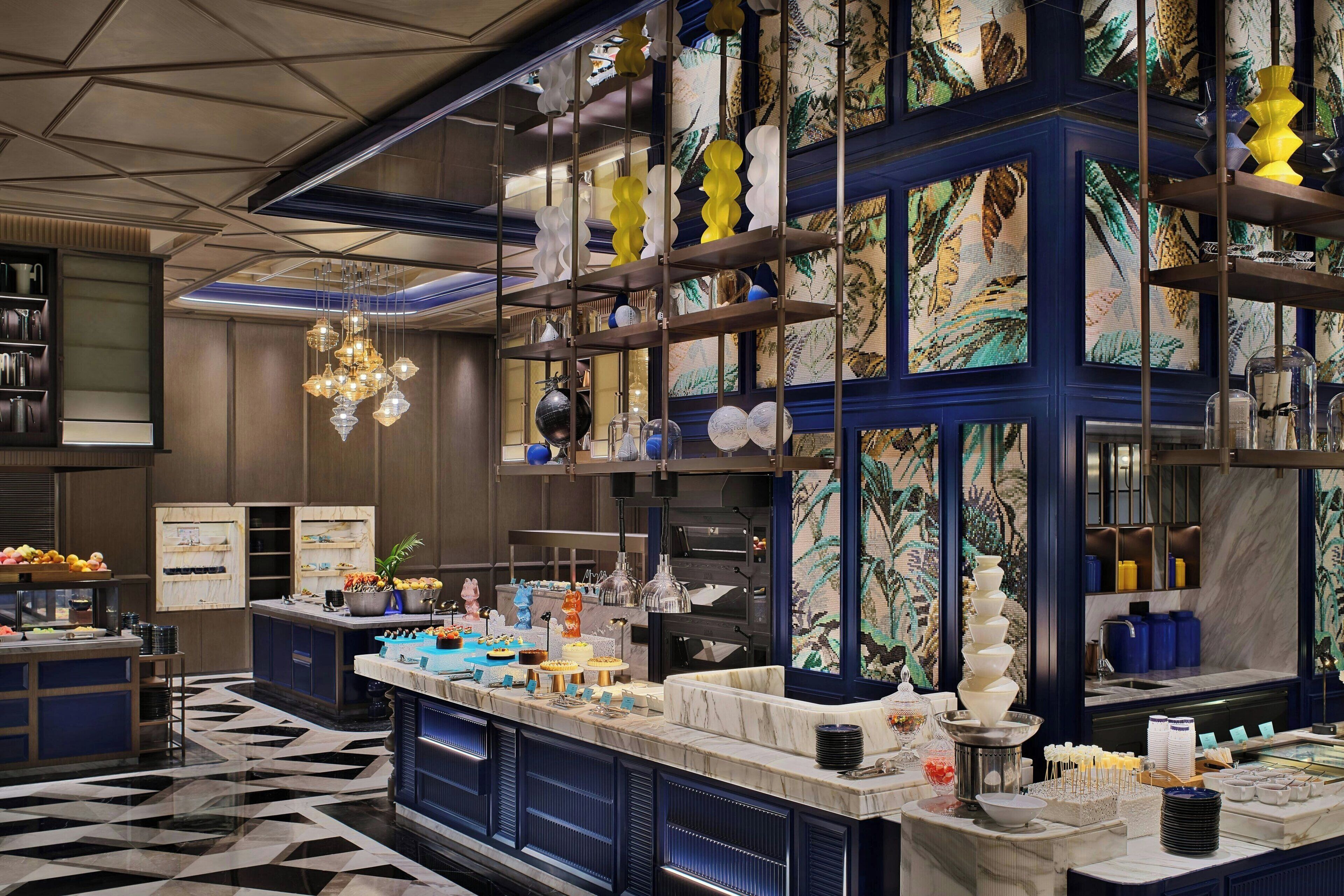 A modern hotel lobby with a marble reception desk, decorative lighting, and a patterned wall.