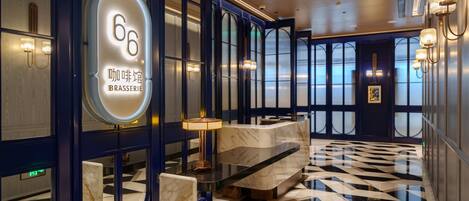 Eine moderne Hotellobby mit Empfangstresen, einer Marmorrezeption und einem geometrisch gemusterten Boden.