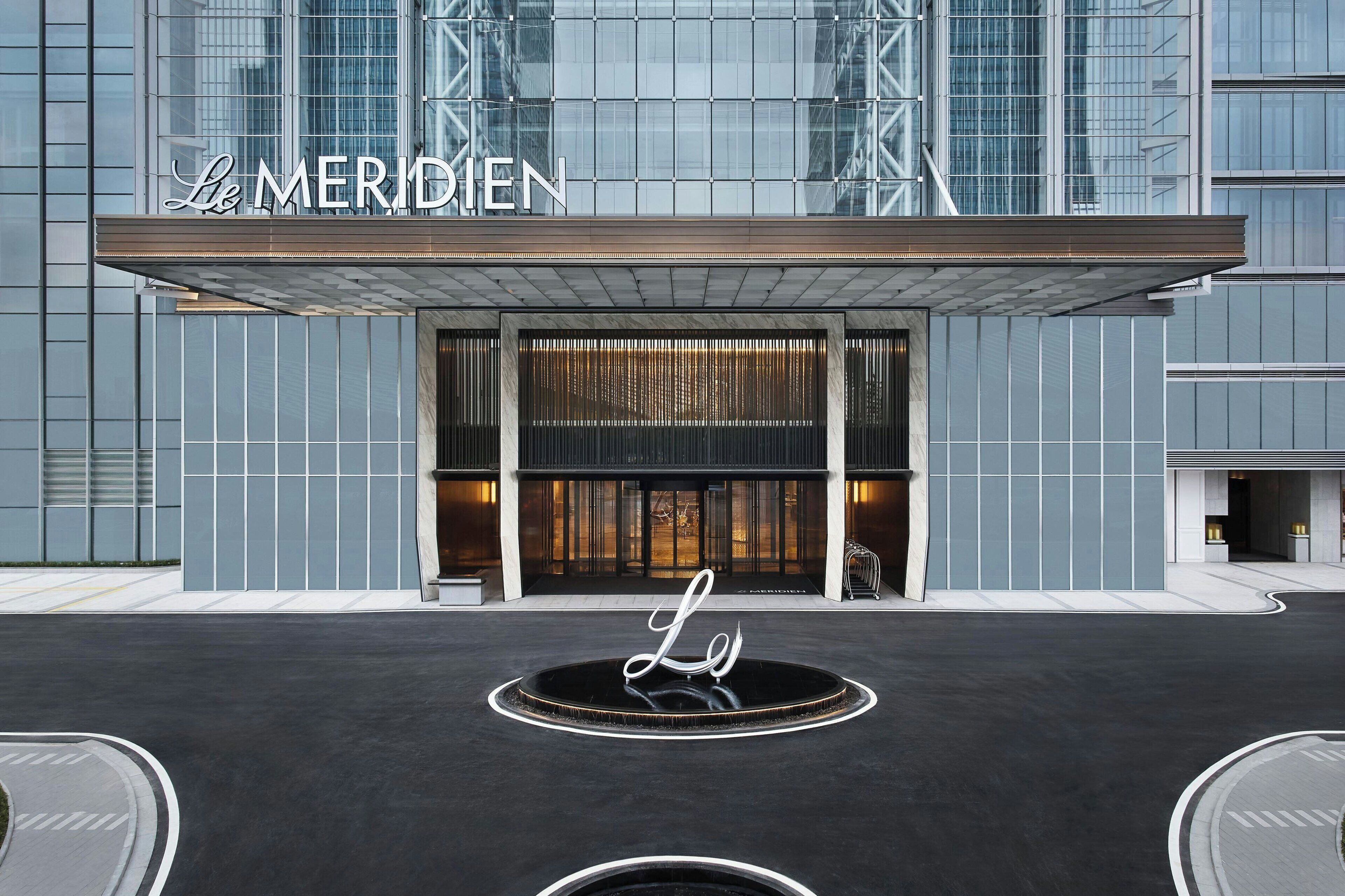 Una entrada de hotel moderna con un letrero destacado que dice "Le MERIDIEN".