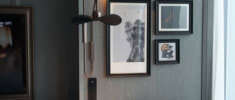 Une pièce moderne avec une table ronde en marbre, deux chaises, un lampadaire et des œuvres d’art encadrées accrochées au mur.
