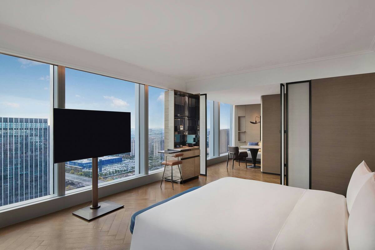 Une chambre d’hôtel moderne dotée d’un grand lit, d’un bureau, d’une télévision et offrant une vue sur la ville.