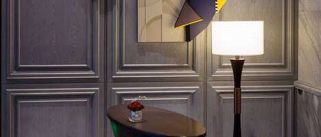 A modern interior with a geometric art piece on the wall, a table with a vase, and a floor lamp.