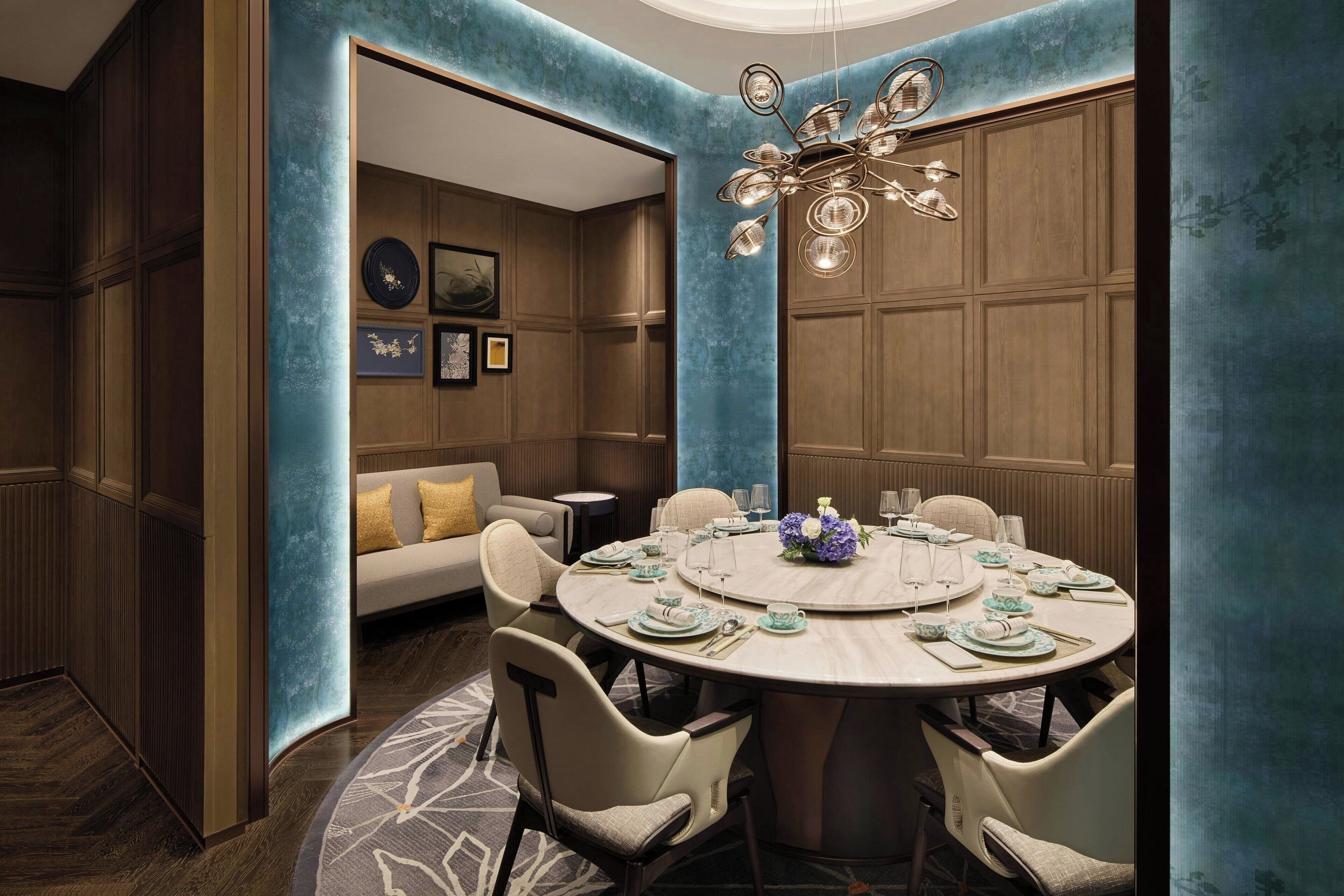 A dining area with a round table set for six, surrounded by chairs.