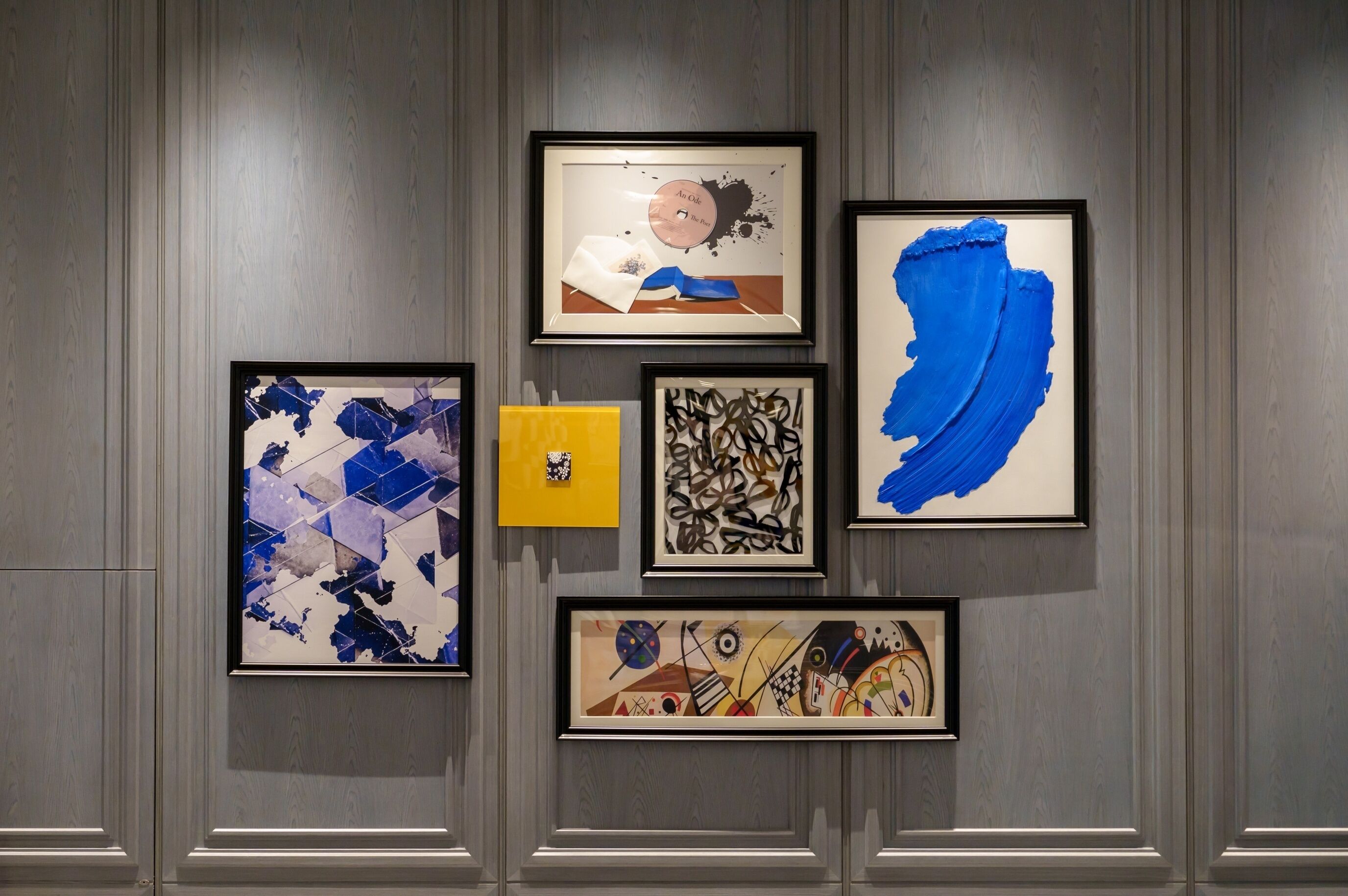 Una pared con cinco obras de arte enmarcadas de diversos estilos abstractos.