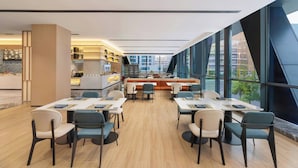 Un restaurante moderno con barra central, zona de estar y amplios ventanales con vistas a la ciudad.