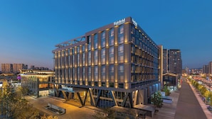 Un hotel moderno con un diseño arquitectónico distintivo, que presenta un llamativo letrero de 'Fairfield by Marriott', varios pisos y una fachada bien iluminada.