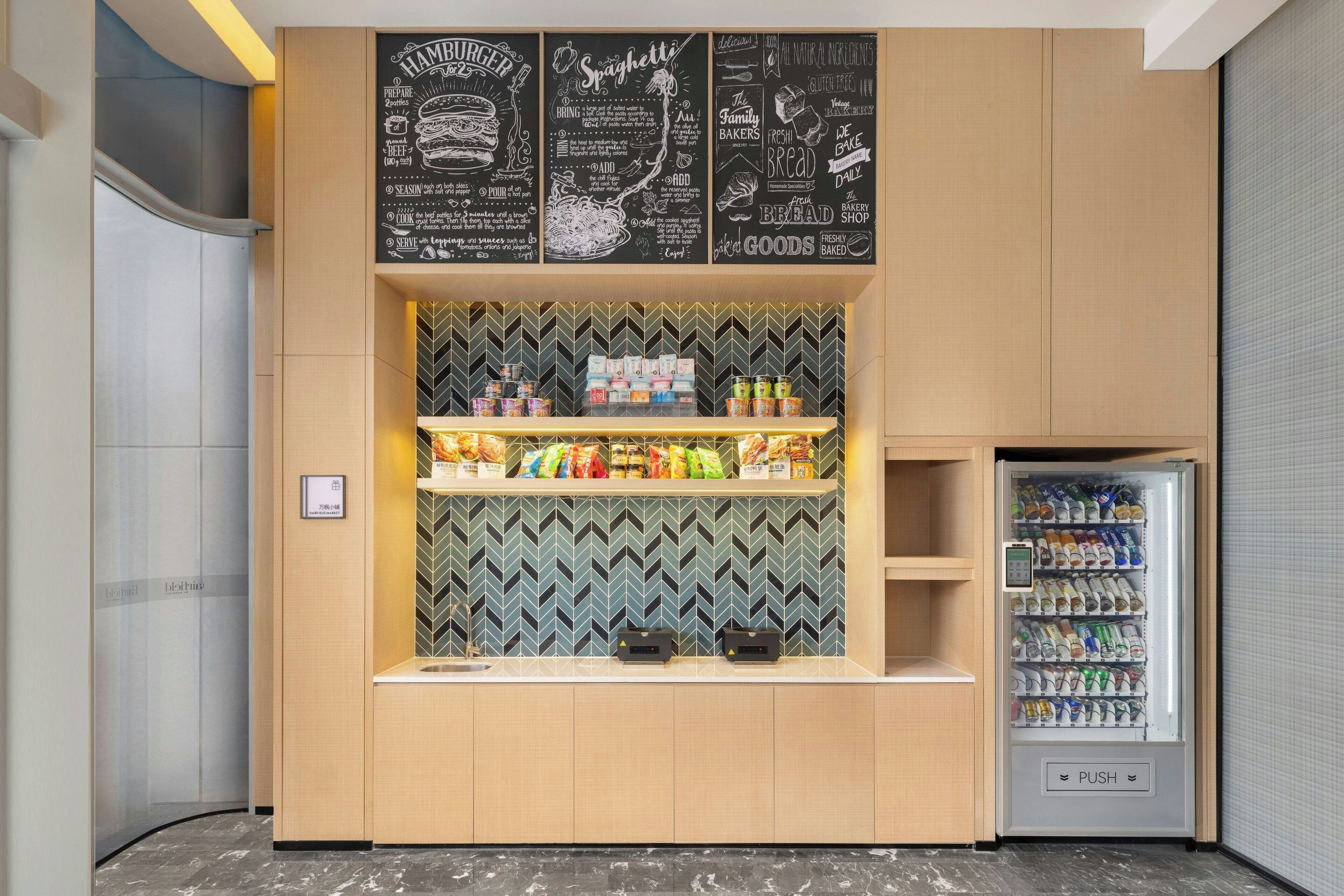 A food kiosk with a chalkboard menu, snack shelves, and a beverage vending machine.