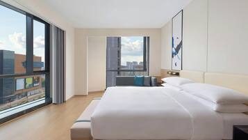 A modern hotel room with a large bed, a view of the city through floor-to-ceiling windows, and a minimalist design.