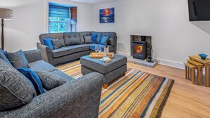 Una sala moderna con un sofá modular, una chimenea, un televisor de pantalla plana y un ventanal grande.
