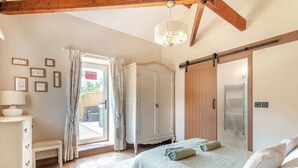 A bedroom with a bed, a nightstand, a wardrobe, a sliding door, and a chandelier. - 2 bedroom accommodation in Elton, near Stockton-on-Tees (Elton, near Stockton-on-Tees)