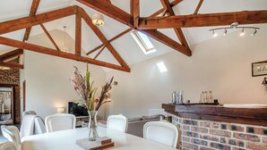 A dining area with a white table, chairs, a vase with flowers, and a brick wall. - 2 bedroom accommodation in Elton, near Stockton-on-Tees (Elton, near Stockton-on-Tees)