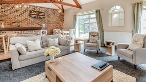 A spacious living room with a brick wall, wooden beams, a fireplace, and a large window. - 2 bedroom accommodation in Elton, near Stockton-on-Tees (Elton, near Stockton-on-Tees)