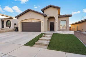 Una casa residenziale con un garage, un prato curato e un vialetto in pietra che conduce all'ingresso.
