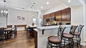 Una cocina moderna con armarios de madera, una isla central con taburetes de bar e iluminación colgante.