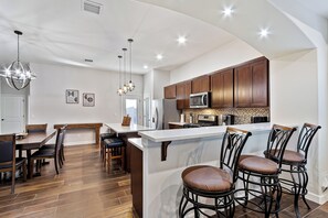 Una cucina moderna con mobili in legno, un'isola centrale con sgabelli da bar e illuminazione a sospensione.