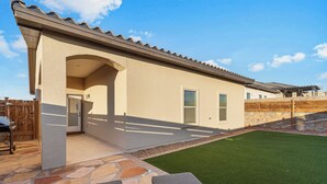 Una casa con patio de piedra, césped verde y valla de madera.