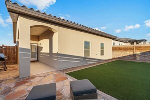 Una casa con un patio in pietra, un prato verde e una recinzione in legno.