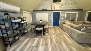 Un espace de vie compact comprenant un coin repas, un canapé et une porte portant l’inscription « LAC ».