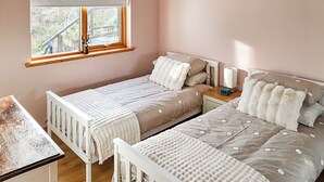 Ein Schlafzimmer mit zwei Betten, einem Fenster mit Blick, einem Nachttisch mit Lampe und einem Bild an der Wand.
