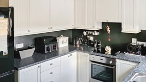 Eine Küche mit weißen Schränken, einer schwarzen Arbeitsplatte, einem Toaster, einem Wasserkocher und einem Spülbecken.