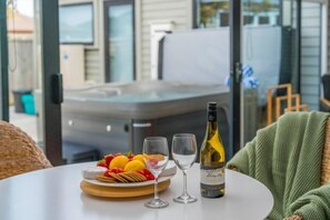 Une table avec une bouteille de vin, deux verres et une assiette de fruits et de crackers.