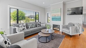 Un salon moderne avec un canapé gris, une table basse ronde et un fauteuil gris.