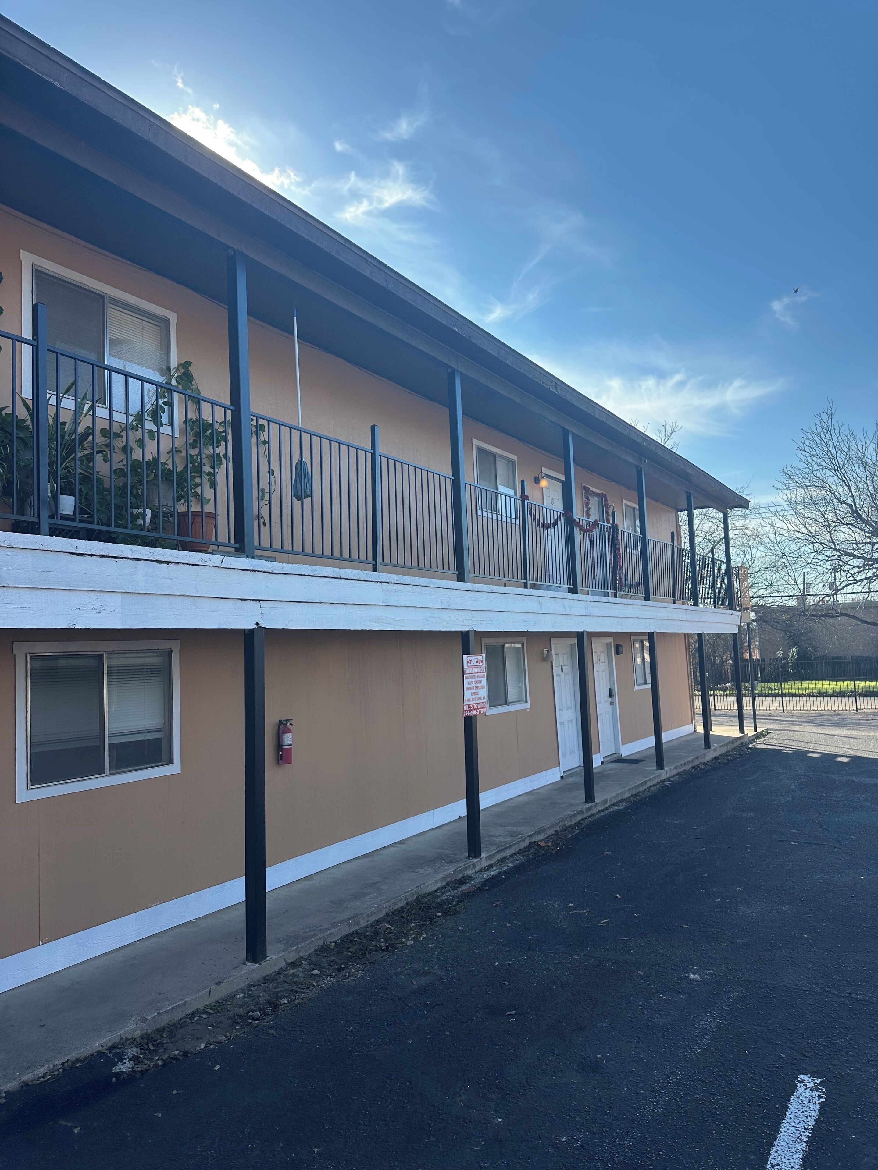 A two-story motel with a flat roof, a covered parking area, and a fire hydrant on the sidewalk.