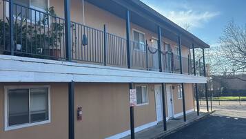 A two-story motel with a flat roof, a covered parking area, and a fire hydrant on the sidewalk.