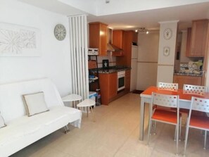 Ein kompakter Wohnraum mit Küchenzeile, einem Essbereich mit Tisch und Stühlen sowie einem Sofa.