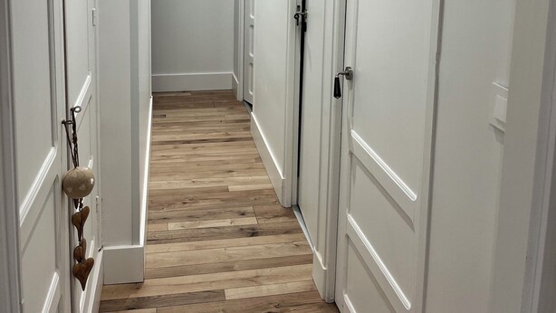 A hallway with white doors and a wooden floor.