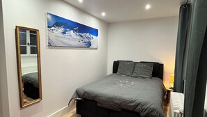 A bedroom with a bed, a mirror, a painting, and a red rug.