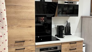 A modern kitchen with wooden cabinetry, a built-in microwave, a coffee maker, and a dishwasher.
