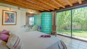 A bedroom with a bed, a bathroom with a sink and mirror, and a large window with a view of greenery. - Beach front home in Ibiza (Ibiza)