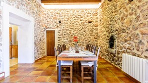 A dining area with a stone wall, wooden ceiling, and tiled floor. - Beach front home in Ibiza (Ibiza)