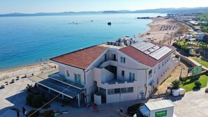 A modern building with a red-tiled roof, large windows, and a flat roof with solar panels. - DOMO 101 - Deluxe Junior Suite with Sea View (Aglientu)