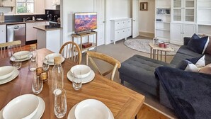 Eine moderne Küche mit Essbereich, ein Wohnzimmer mit Sofa und Fernseher.