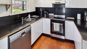 Eine kleine Küche mit Geschirrspüler, Backofen und Kaffeemaschine.