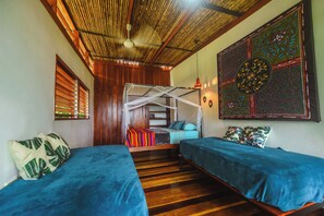 Quarto com duas camas, teto de madeira e um objeto decorativo na parede.