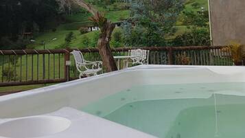 A hot tub with a view of a green landscape.