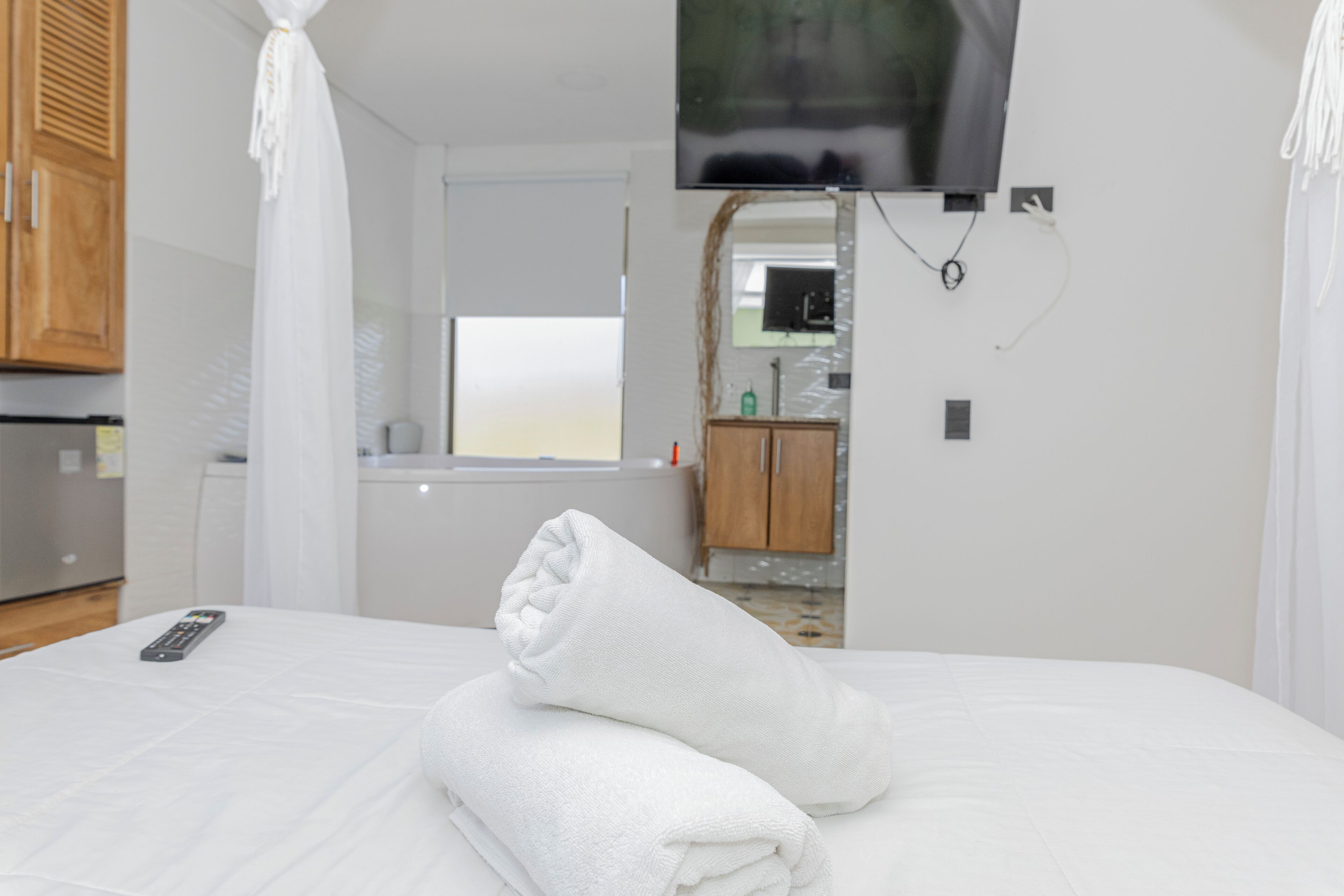 Una cama bien hecha con sábanas blancas y un control remoto encima.