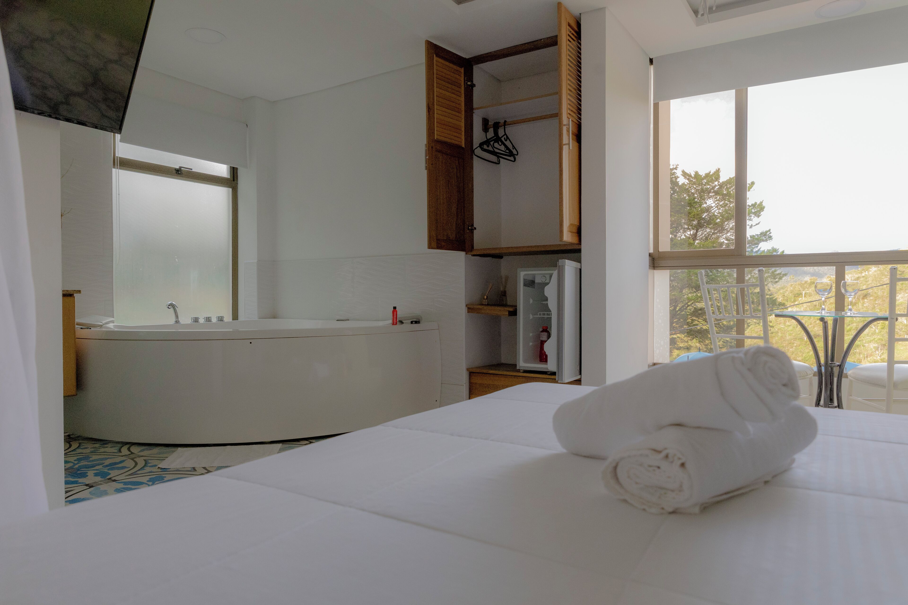 Une salle de bain moderne avec une baignoire, un grand miroir et une fenêtre donnant sur un balcon.