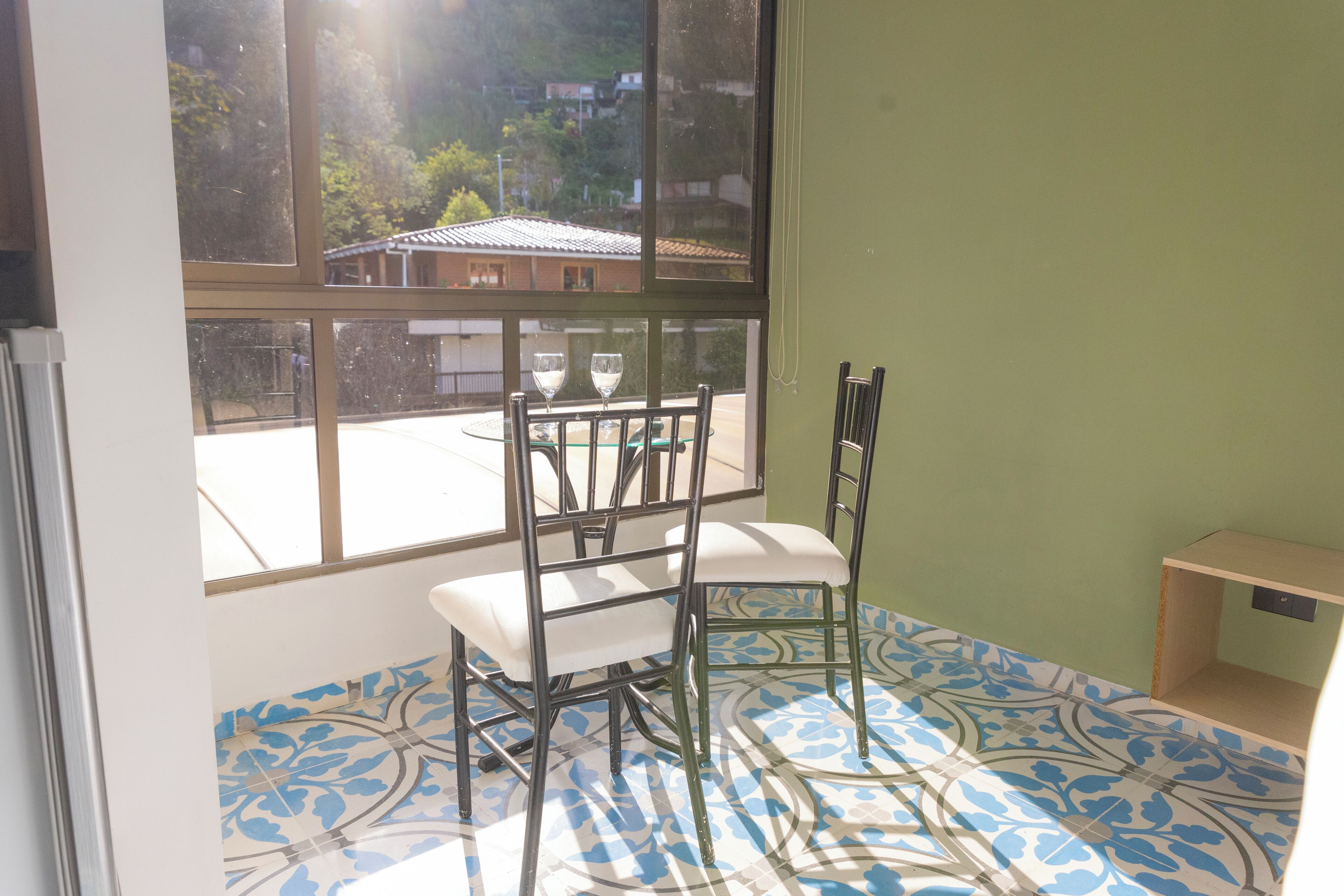 A room with a large window, a tiled floor, and a chair.