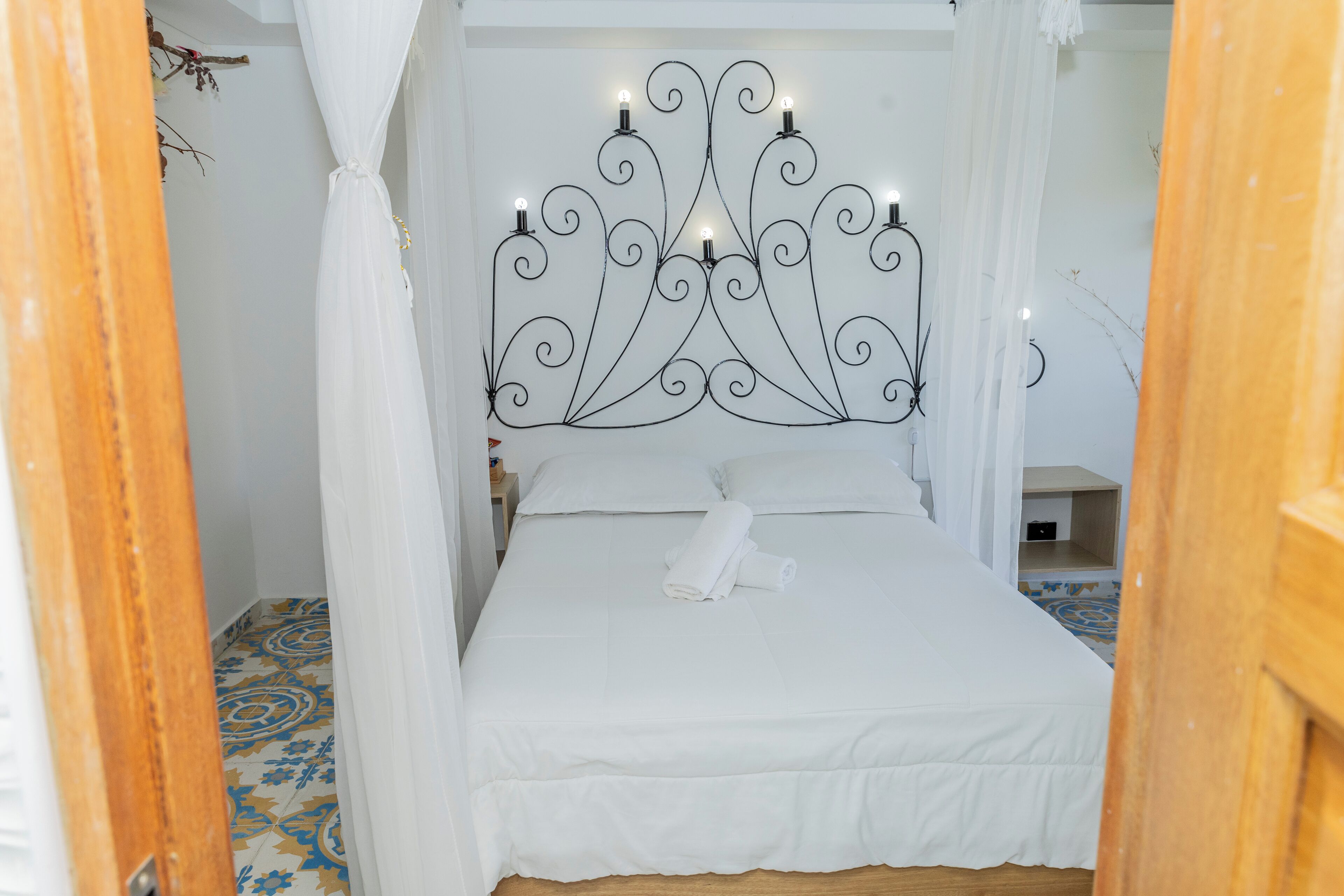 Un lit bien fait, surmonté d’un baldaquin blanc et doté d’une tête de lit décorative agrémentée de lumières.