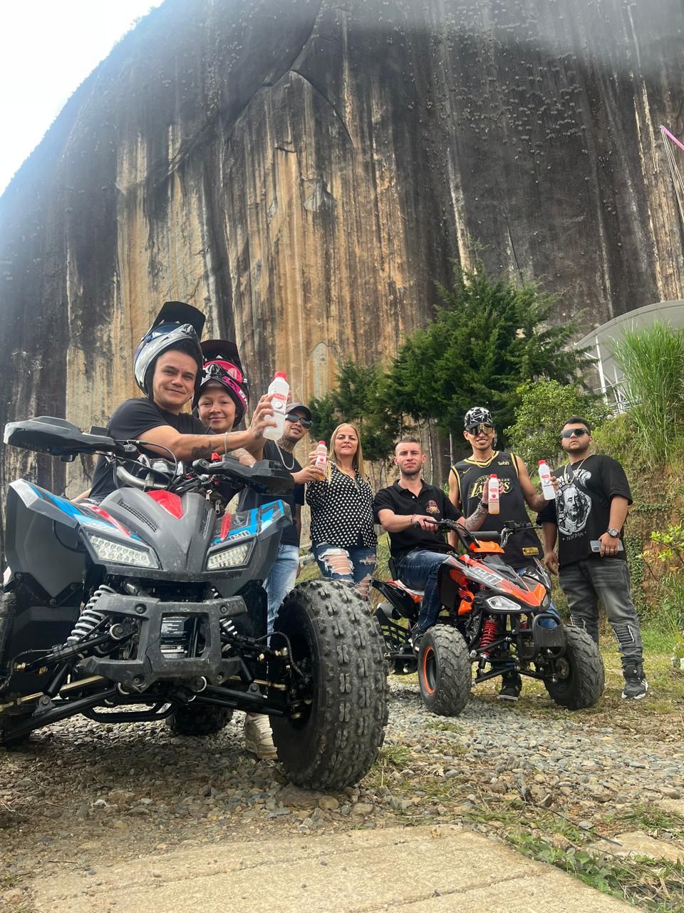 Eine Gruppe von Personen fährt mit Quads vor einer großen Felsformation.