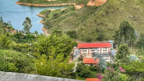 A coastal property with a red-roofed building surrounded by lush greenery and water bodies. - Hotel Bahía Del Faro (Guatapé)