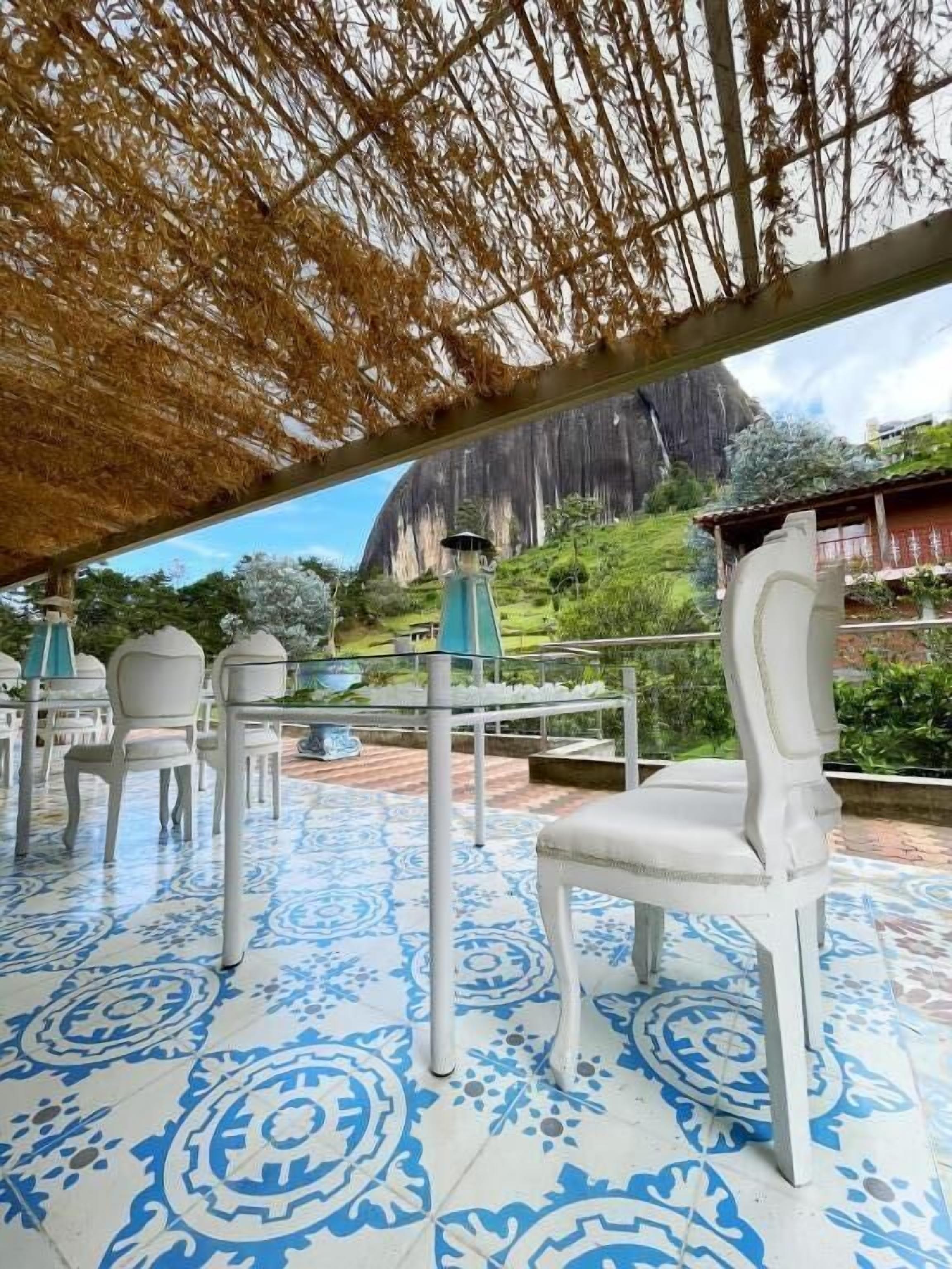 Un espace extérieur aménagé avec des chaises blanches et un sol à motifs, offrant une vue sur un paysage montagneux.