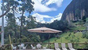 A hot tub on a wooden deck with outdoor seating and a view of a mountainous landscape. - Hotel Bahía Del Faro (Guatapé)
